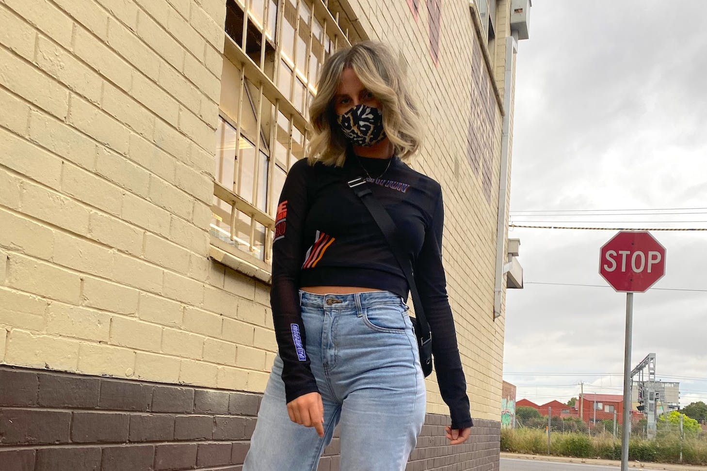 A girl wearing a reusable cloth mask walks down the footpath.